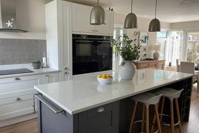 This is an example of a medium sized contemporary u-shaped kitchen/diner in West Midlands with a built-in sink, quartz worktops, grey splashback, engineered quartz splashback, an island and grey worktops.