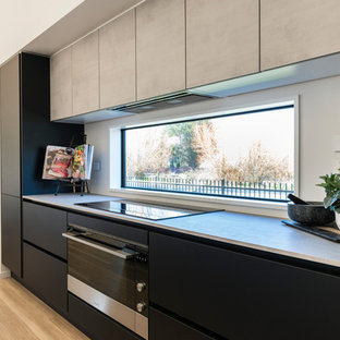 Zweizeilige, Mittelgroße Moderne Küche mit Vorratsschrank, Einbauwaschbecken, flächenbündigen Schrankfronten, schwarzen Schränken, Laminat-Arbeitsplatte, Küchenrückwand in Weiß, Rückwand-Fenster, Küchengeräten aus Edelstahl, Laminat, Kücheninsel und braunem Boden in Christchurch