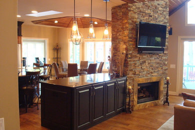 Living room - large traditional open concept medium tone wood floor and brown floor living room idea in Other with beige walls, a two-sided fireplace, a stone fireplace and a wall-mounted tv