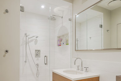 Inspiration for a mid-sized contemporary 3/4 bathroom in New York with flat-panel cabinets, medium wood cabinets, an alcove shower, a one-piece toilet, white tile, ceramic tile, grey walls, marble floors, an undermount sink, engineered quartz benchtops, multi-coloured floor, a hinged shower door and white benchtops.