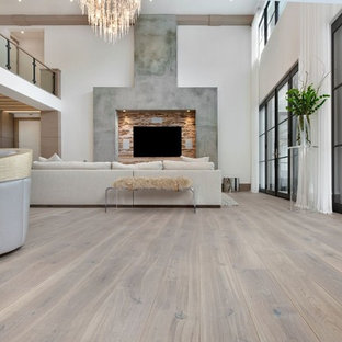 Inredning av ett modernt mycket stort allrum med öppen planlösning, med vita väggar, ljust trägolv och en väggmonterad TV