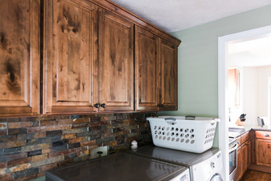 Small elegant single-wall medium tone wood floor and brown floor dedicated laundry room photo in Other with raised-panel cabinets, medium tone wood cabinets, gray walls and a side-by-side washer/dryer