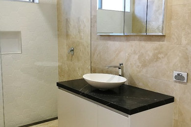 This is an example of a mid-sized contemporary bathroom in Sydney with white cabinets and marble benchtops.