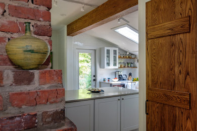 Small farmhouse u-shaped medium tone wood floor and brown floor open concept kitchen photo in Raleigh with a farmhouse sink, beaded inset cabinets, white cabinets, quartz countertops, white backsplash, subway tile backsplash, stainless steel appliances, an island and multicolored countertops