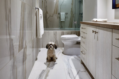 Inspiration for a mid-sized contemporary white tile and ceramic tile ceramic tile, white floor and single-sink tub/shower combo remodel in Toronto with flat-panel cabinets, beige cabinets, a one-piece toilet, white walls, an undermount sink, quartzite countertops, a hinged shower door, brown countertops and a freestanding vanity