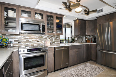 Inspiration for a large coastal l-shaped eat-in kitchen remodel in Miami with flat-panel cabinets, dark wood cabinets, granite countertops, multicolored backsplash, glass tile backsplash, stainless steel appliances and an island