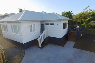 Mid-sized traditional one-storey white house exterior in Auckland with wood siding, a gable roof and a metal roof.
