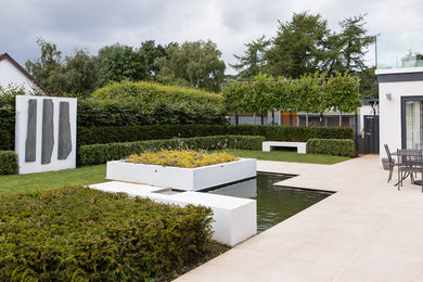 Inspiration for a mid-sized contemporary backyard full sun garden in Edinburgh with with pond and natural stone pavers.