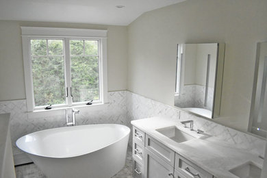 This is an example of a mid-sized transitional master bathroom in Boston with grey cabinets, a japanese tub, marble benchtops, beige benchtops, a double vanity and a floating vanity.