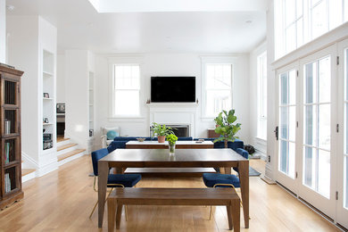 Example of a transitional open concept light wood floor and beige floor living room design in Other with white walls, a standard fireplace and a wall-mounted tv