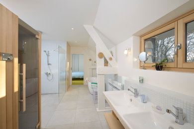 This is an example of a large contemporary bathroom in Angers with light wood cabinets, a drop-in tub, a curbless shower, white walls, ceramic floors and a console sink.