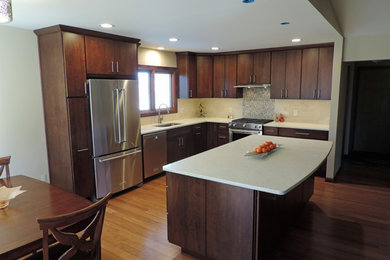 Modelo de cocina minimalista de tamaño medio con armarios con paneles lisos, electrodomésticos de acero inoxidable y una isla