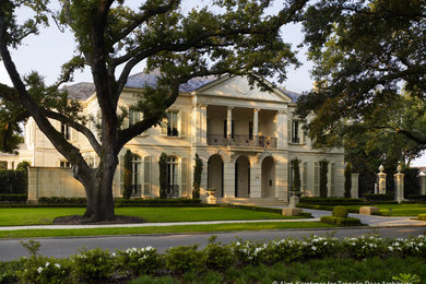 Expansive traditional three-storey beige house exterior in New Orleans with stone veneer, a hip roof and a tile roof.