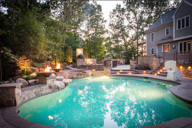 Ejemplo de piscina con fuente natural clásica de tamaño medio a medida en patio trasero con adoquines de piedra natural