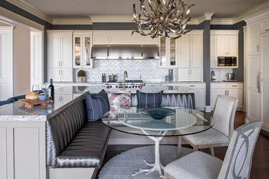 Example of a large transitional l-shaped dark wood floor and brown floor eat-in kitchen design in Minneapolis with a farmhouse sink, flat-panel cabinets, white cabinets, solid surface countertops, gray backsplash, marble backsplash, stainless steel appliances, an island and white countertops