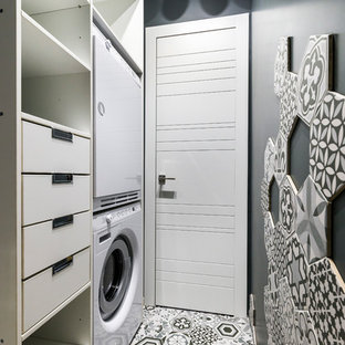 This is an example of a contemporary separated utility room in Moscow with black walls and a stacked washer and dryer.