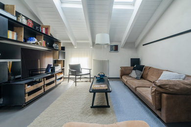Cette image montre une grande salle de séjour minimaliste ouverte avec une bibliothèque ou un coin lecture, un mur blanc, une cheminée double-face, un manteau de cheminée en pierre, un téléviseur encastré, un sol gris et poutres apparentes.