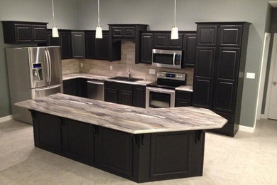 Example of a l-shaped kitchen design in Other with black cabinets, gray backsplash, stainless steel appliances and an island