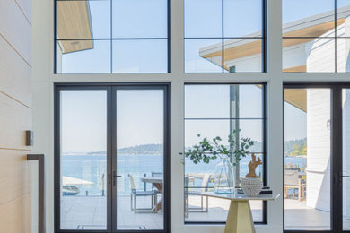 Photo of a beach style foyer in Seattle with white walls, light hardwood floors, a single front door, a light wood front door and vaulted.