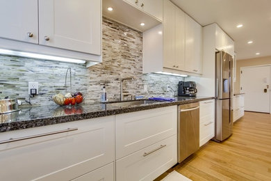 Inspiration for a mid-sized transitional galley medium tone wood floor enclosed kitchen remodel in Los Angeles with an undermount sink, shaker cabinets, white cabinets, granite countertops, multicolored backsplash, stainless steel appliances, matchstick tile backsplash and no island
