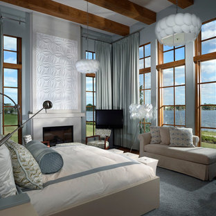 Großes Modernes Hauptschlafzimmer mit blauer Wandfarbe, Kamin, dunklem Holzboden, Kaminumrandung aus Beton und braunem Boden in Orlando