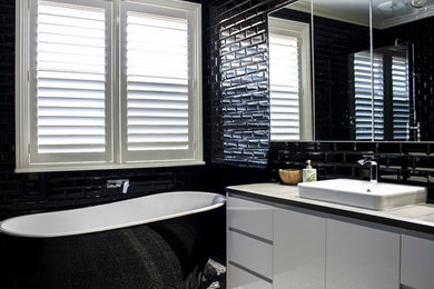 Photo of a large modern bathroom in Sydney with flat-panel cabinets, white cabinets, a freestanding tub, an open shower, black tile, subway tile, black walls, ceramic floors, a drop-in sink, limestone benchtops, grey floor, an open shower, white benchtops, a single vanity and a built-in vanity.