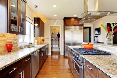Example of a mid-sized transitional galley medium tone wood floor eat-in kitchen design in Seattle with a double-bowl sink, recessed-panel cabinets, dark wood cabinets, granite countertops, beige backsplash, stone tile backsplash, stainless steel appliances and no island