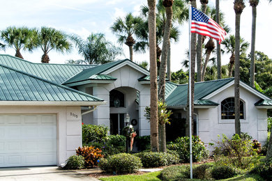 Inspiration for a large transitional one-storey stucco beige house exterior in Orlando with a gable roof and a metal roof.