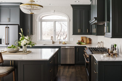 Inspiration for a transitional l-shaped dark wood floor and brown floor kitchen remodel in Kansas City with an undermount sink, shaker cabinets, gray cabinets, white backsplash, stainless steel appliances, an island and white countertops