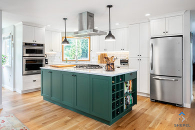 Mid-sized transitional l-shaped light wood floor and brown floor open concept kitchen photo in Seattle with an undermount sink, recessed-panel cabinets, white cabinets, quartz countertops, white backsplash, subway tile backsplash, stainless steel appliances, an island and white countertops