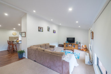 This is an example of a mid-sized enclosed family room in Other with white walls, carpet, a freestanding tv and beige floor.