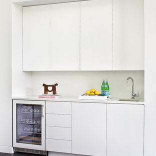 ニューヨークの中サイズのモダンスタイルのおしゃれなウェットバー (アンダーカウンターシンク、フラットパネル扉のキャビネット、白いキャビネット、人工大理石カウンター、磁器タイルの床、黒い床) の写真