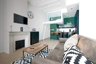 Inspiration pour un petit salon mansardé ou avec mezzanine minimaliste avec un mur blanc, parquet clair, un manteau de cheminée en pierre, un téléviseur fixé au mur et un sol marron.