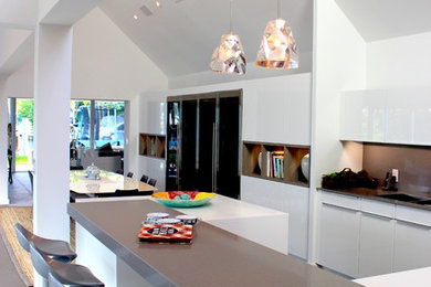 Large trendy l-shaped eat-in kitchen photo in Miami with flat-panel cabinets, white cabinets, gray backsplash and stainless steel appliances