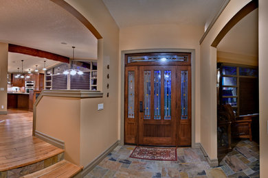 Inspiration for a large timeless slate floor entryway remodel in Calgary with beige walls and a dark wood front door