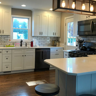 Mid-sized eclectic kitchen pantry remodeling - Inspiration for a mid-sized eclectic u-shaped dark wood floor and brown floor kitchen pantry remodel in Bridgeport with an undermount sink, shaker cabinets, white cabinets, quartz countertops, white backsplash, ceramic backsplash, black appliances and no island