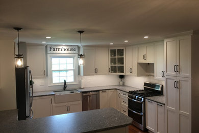 Large cottage u-shaped medium tone wood floor and brown floor eat-in kitchen photo with a farmhouse sink, recessed-panel cabinets, white cabinets, quartz countertops, white backsplash, porcelain backsplash, stainless steel appliances, a peninsula and gray countertops