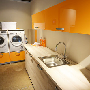Inspiration for a contemporary utility room in London with flat-panel cabinets, orange cabinets, laminate countertops and a stacked washer and dryer.