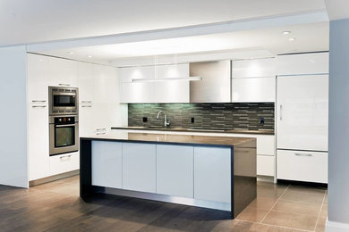 Example of a mid-sized minimalist single-wall brown floor kitchen design in Orange County with flat-panel cabinets, white cabinets, stainless steel appliances, an island, multicolored backsplash and matchstick tile backsplash