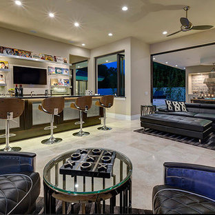 Cette image montre une très grande salle de cinéma design ouverte avec un mur beige, un sol en travertin et un téléviseur fixé au mur.