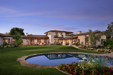 Example of a huge mountain style beige two-story stucco gable roof design in Phoenix