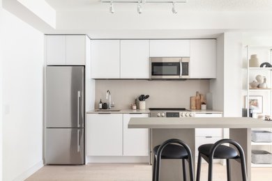 Small danish single-wall light wood floor and beige floor eat-in kitchen photo in Toronto with an undermount sink, flat-panel cabinets, white cabinets, quartz countertops, gray backsplash, quartz backsplash, stainless steel appliances, an island and gray countertops