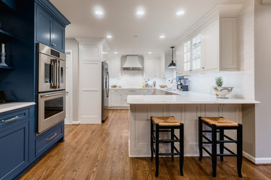 Enclosed kitchen - large transitional l-shaped medium tone wood floor and brown floor enclosed kitchen idea in DC Metro with an undermount sink, shaker cabinets, white cabinets, white backsplash, subway tile backsplash, stainless steel appliances, a peninsula and white countertops