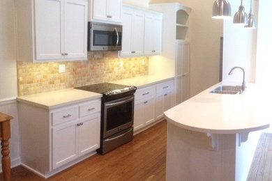 Mid-sized elegant galley medium tone wood floor enclosed kitchen photo in Orange County with a double-bowl sink, shaker cabinets, white cabinets, quartz countertops, multicolored backsplash, stone tile backsplash, stainless steel appliances and a peninsula