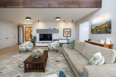 Пример оригинального дизайна: открытая гостиная комната в современном стиле с светлым паркетным полом, телевизором на стене и сводчатым потолком