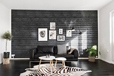 Large scandinavian open concept living room in Stockholm with black walls, black floor and dark hardwood floors.