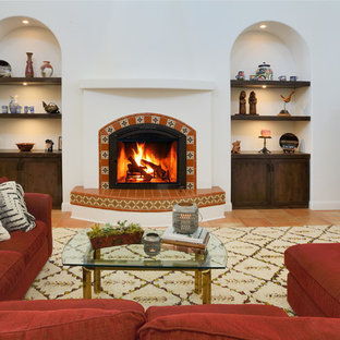 Immagine di un soggiorno mediterraneo aperto con cornice del camino piastrellata, sala formale, pareti bianche, pavimento in terracotta, TV nascosta e pavimento arancione