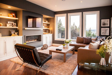Example of a trendy medium tone wood floor family room design in Other with black walls, a ribbon fireplace and a wall-mounted tv