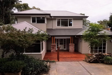 Photo of a large traditional two-storey grey house exterior in Melbourne with wood siding, a hip roof, a metal roof, a grey roof and board and batten siding.