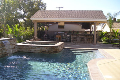 Example of a large tuscan backyard stone and custom-shaped lap hot tub design in Los Angeles
